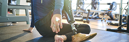 Athlete with amputee leg sitting on the floor and resting in health club