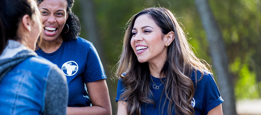 Group of people in a park smiling and laughing while two of them shake hands.