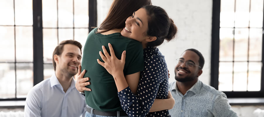 Two people hugging and smiling at group recovery session.