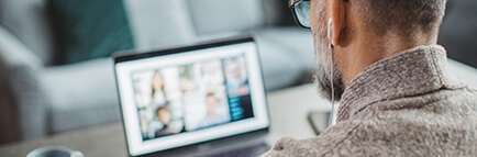 Man looking at a laptop with headphones on