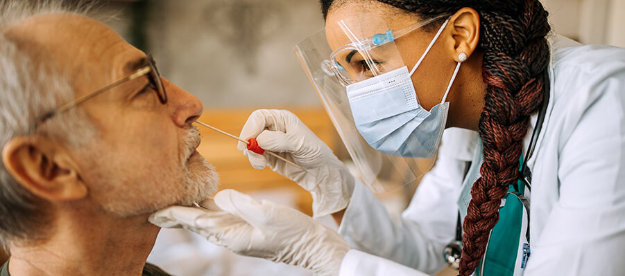 Doctor taking nasal swab of senior patient for COVID-19 testing.