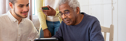 Man and women helping an older man on a tablet