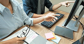 Two people seated together discussing and responding to an online survey